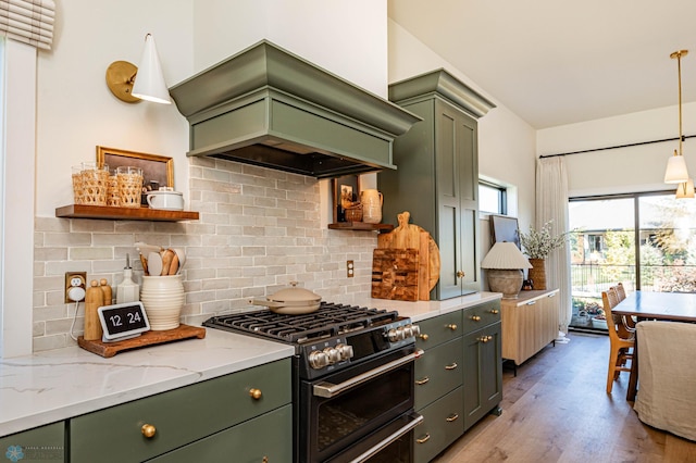 kitchen featuring light stone counters, pendant lighting, stainless steel stove, green cabinets, and light hardwood / wood-style floors