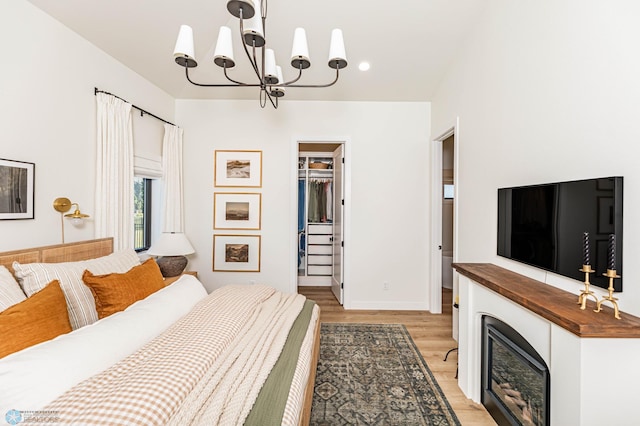 bedroom featuring a notable chandelier, a closet, light hardwood / wood-style floors, and a walk in closet