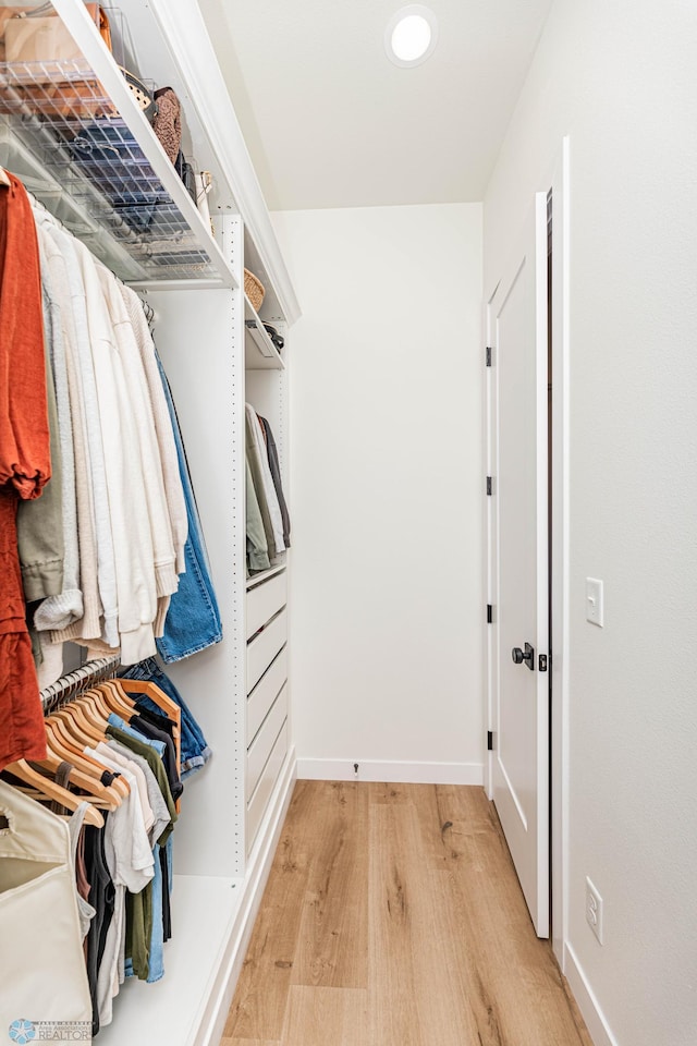 walk in closet with light hardwood / wood-style floors