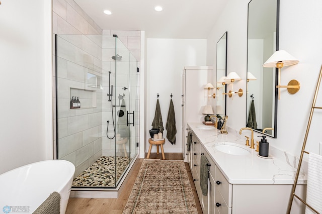 bathroom with wood-type flooring, independent shower and bath, and vanity