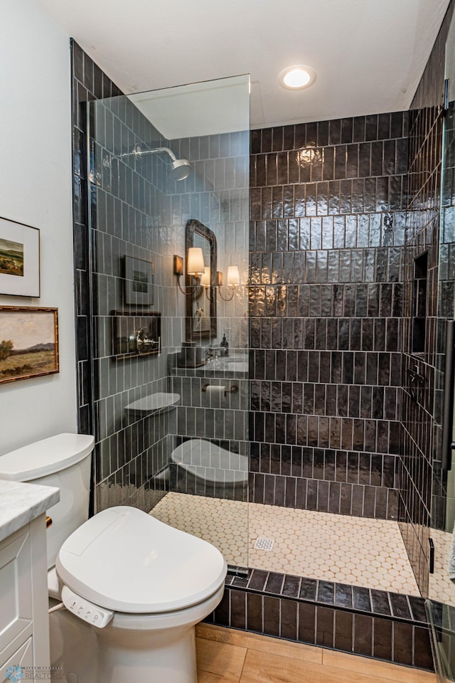 bathroom with a tile shower, vanity, tile patterned flooring, and toilet