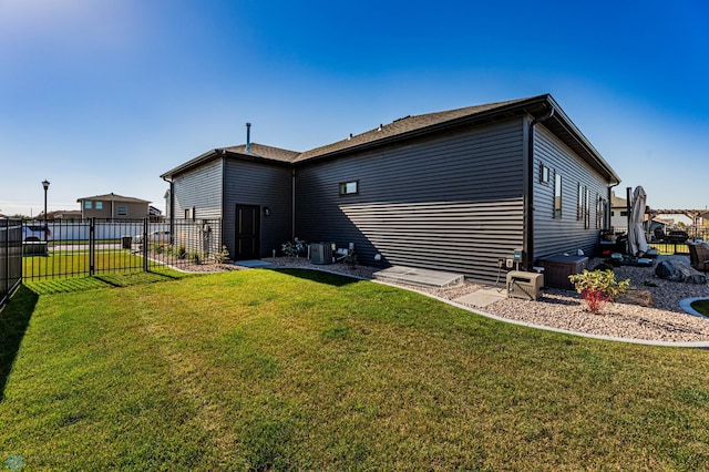 rear view of property with central AC unit and a yard