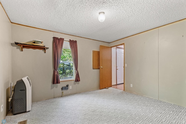 empty room featuring carpet floors, a textured ceiling, and ornamental molding