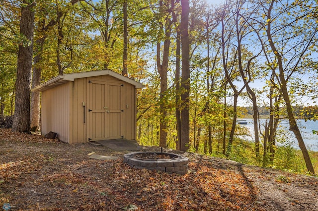 view of outdoor structure featuring a water view and a fire pit