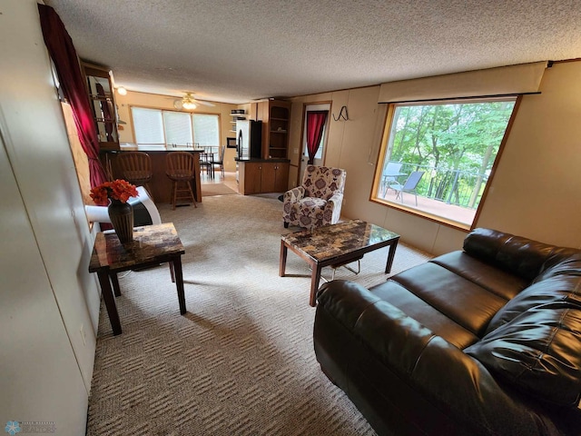 living room with light carpet, a textured ceiling, and ceiling fan