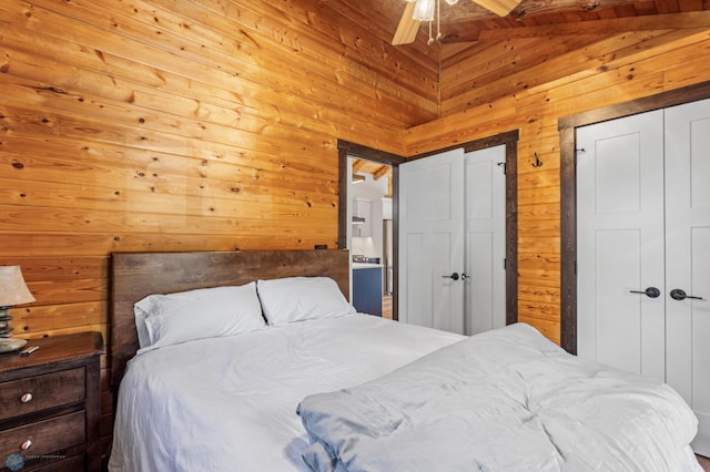 bedroom featuring connected bathroom, vaulted ceiling with beams, ceiling fan, and wood walls