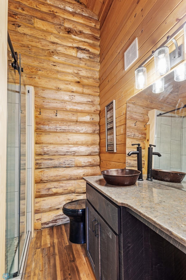 bathroom with vanity, an enclosed shower, rustic walls, hardwood / wood-style flooring, and toilet