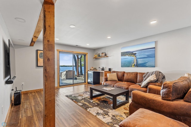 living room with bar, a water view, and hardwood / wood-style flooring