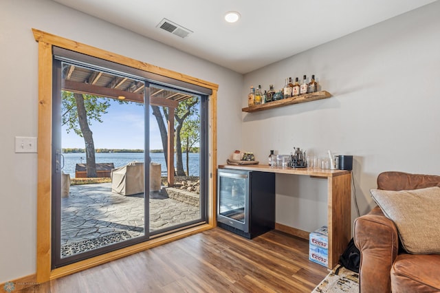 bar featuring a water view, dark hardwood / wood-style flooring, and wine cooler