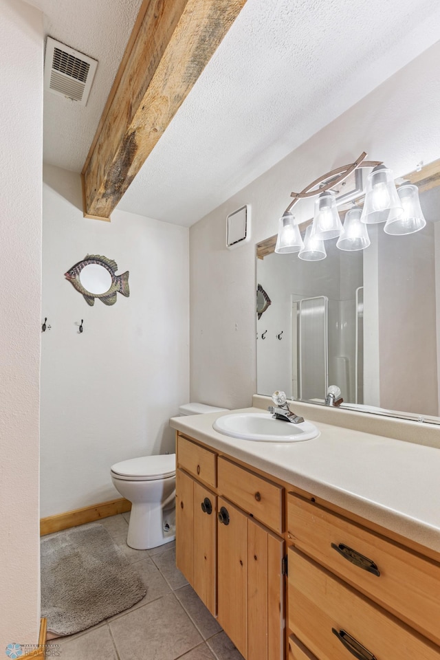 bathroom with a textured ceiling, walk in shower, tile patterned floors, vanity, and toilet