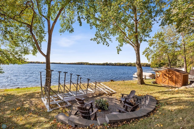 view of yard featuring a dock, a water view, a storage unit, and a fire pit