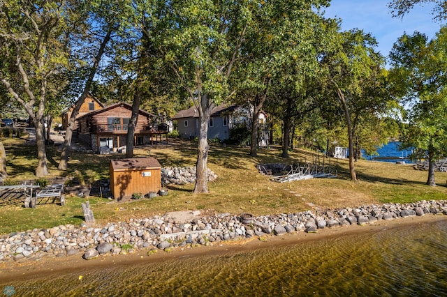 view of front facade with a shed, a water view, and a front lawn