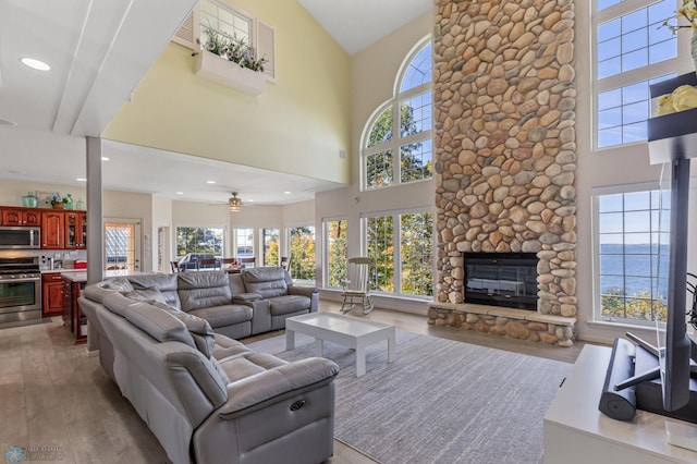 living room featuring a water view, a wealth of natural light, a fireplace, and hardwood / wood-style floors