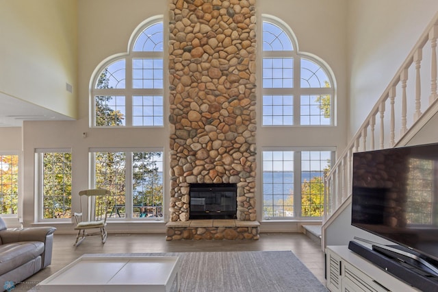 unfurnished living room with a stone fireplace, a towering ceiling, and plenty of natural light