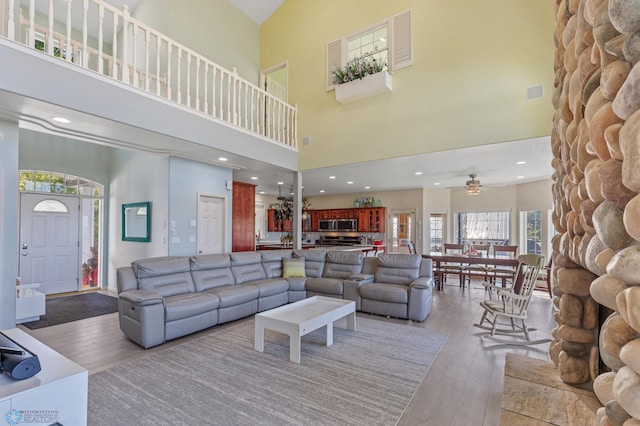 living room featuring a high ceiling, wood-type flooring, and ceiling fan