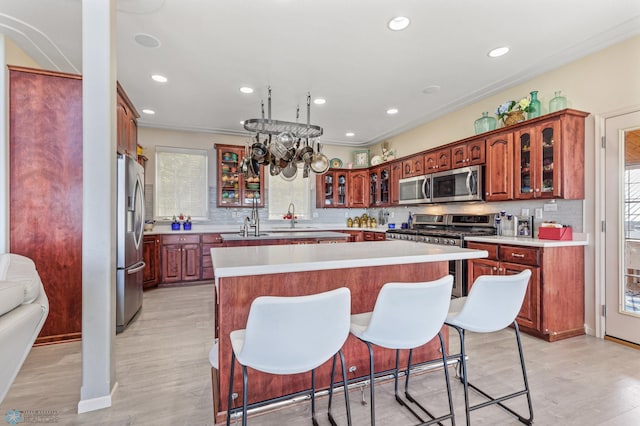 kitchen featuring tasteful backsplash, a kitchen island, a kitchen bar, light hardwood / wood-style flooring, and stainless steel appliances