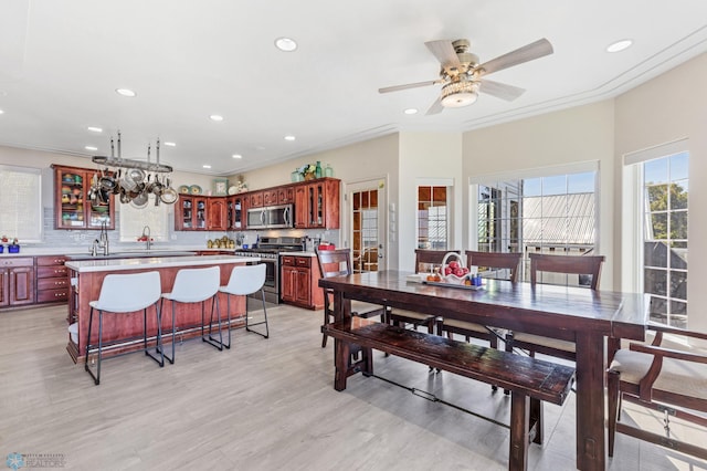 dining space featuring ornamental molding, light wood-type flooring, and ceiling fan