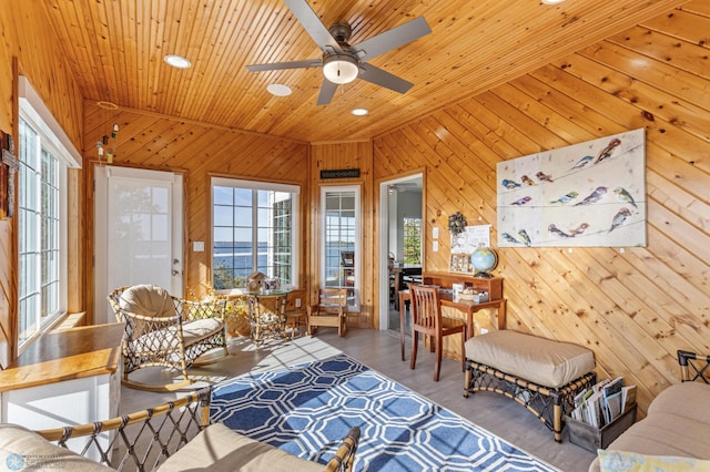 interior space with lofted ceiling, light hardwood / wood-style flooring, ceiling fan, and wood walls