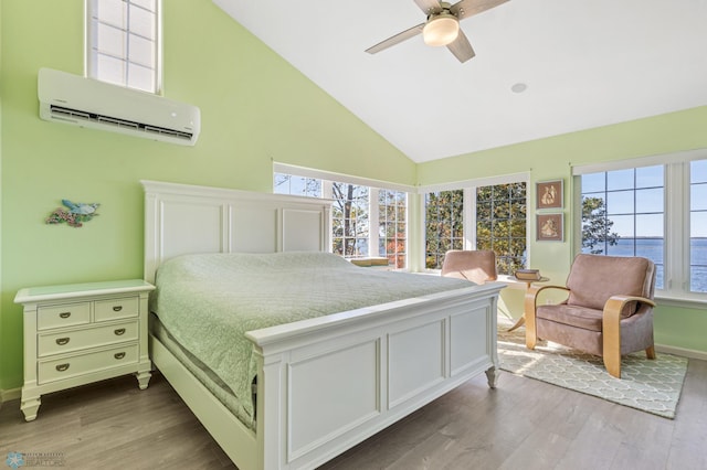 bedroom featuring a wall unit AC, hardwood / wood-style flooring, a water view, high vaulted ceiling, and ceiling fan