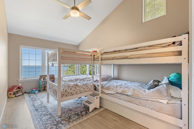 bedroom with lofted ceiling, hardwood / wood-style flooring, a water view, and ceiling fan