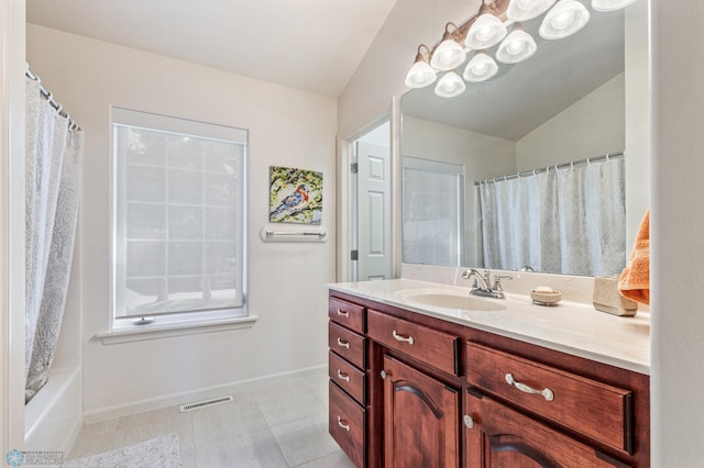 bathroom featuring vanity, lofted ceiling, and shower / tub combo