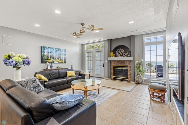 tiled living room featuring ornamental molding, a textured ceiling, a fireplace, and ceiling fan