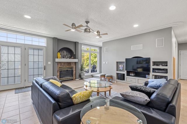 living room featuring a premium fireplace, light tile patterned flooring, a textured ceiling, and ceiling fan