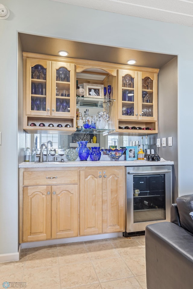 bar with wine cooler, light brown cabinetry, and light tile patterned floors