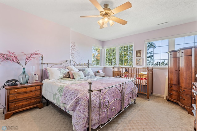 carpeted bedroom with multiple windows, a textured ceiling, and ceiling fan