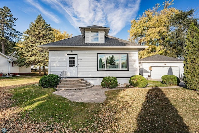 bungalow-style home with an outbuilding, a garage, and a front lawn