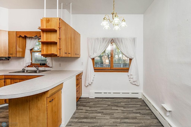 kitchen with hanging light fixtures, sink, dark wood-type flooring, a baseboard radiator, and decorative backsplash