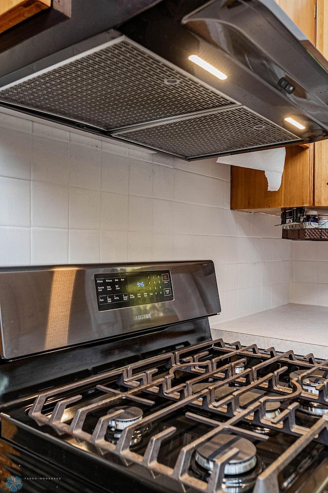 details featuring decorative backsplash, black range with gas cooktop, and range hood