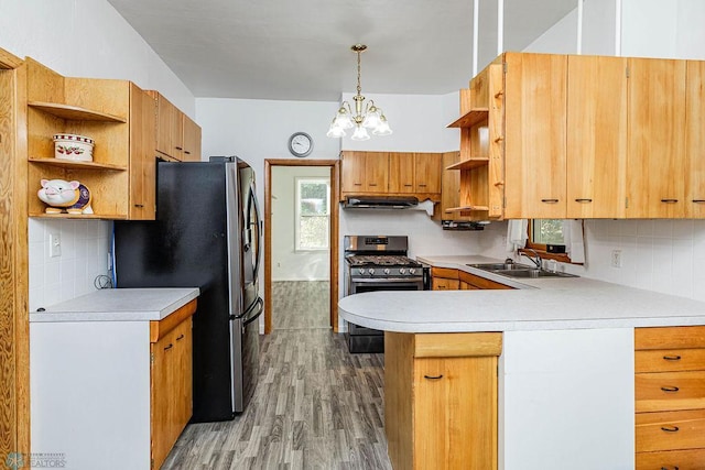 kitchen with a chandelier, kitchen peninsula, hanging light fixtures, stainless steel appliances, and hardwood / wood-style floors