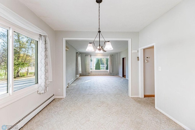 unfurnished dining area featuring light colored carpet, an inviting chandelier, plenty of natural light, and a baseboard heating unit