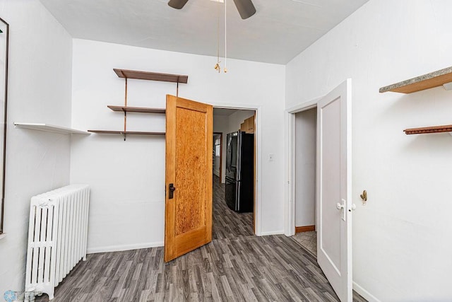 bedroom with a closet, radiator, ceiling fan, dark hardwood / wood-style floors, and black fridge