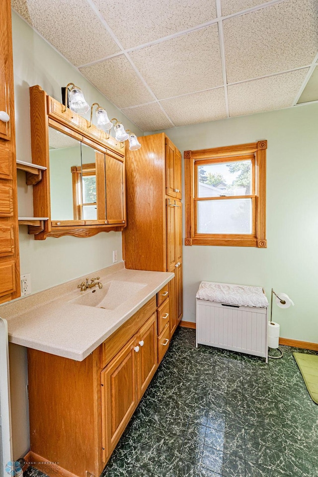 bathroom with radiator, vanity, a drop ceiling, and a wealth of natural light