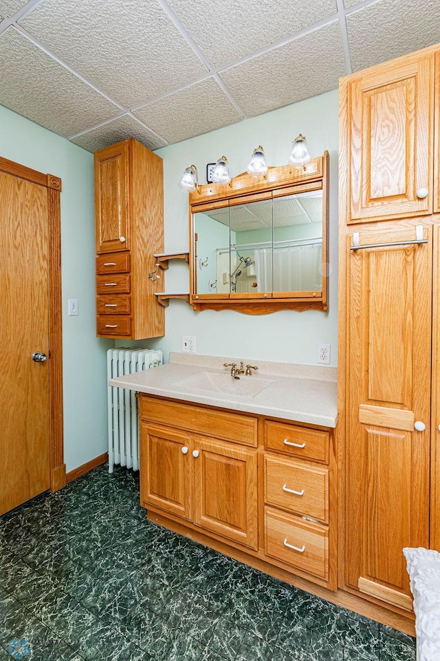 bathroom featuring a drop ceiling, vanity, and radiator heating unit