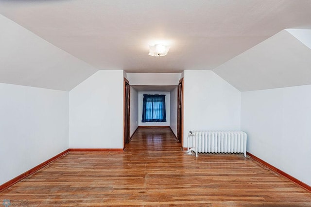 bonus room featuring hardwood / wood-style flooring, vaulted ceiling, and radiator heating unit