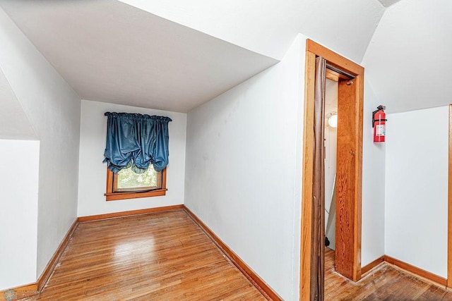 hallway featuring vaulted ceiling and light hardwood / wood-style floors