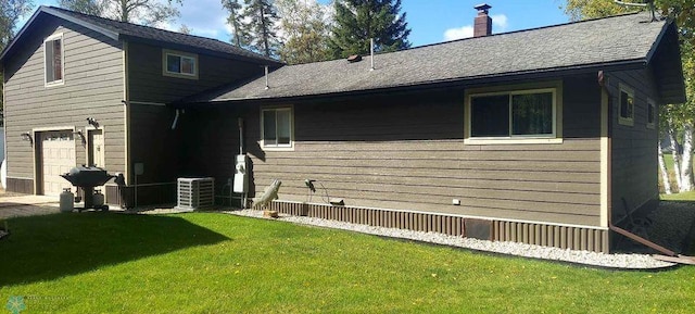 exterior space featuring a garage, a lawn, and central AC unit