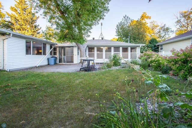 back of property featuring a patio, a sunroom, and a lawn