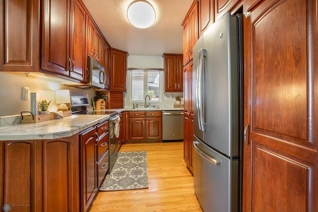 kitchen featuring appliances with stainless steel finishes, sink, and light hardwood / wood-style floors