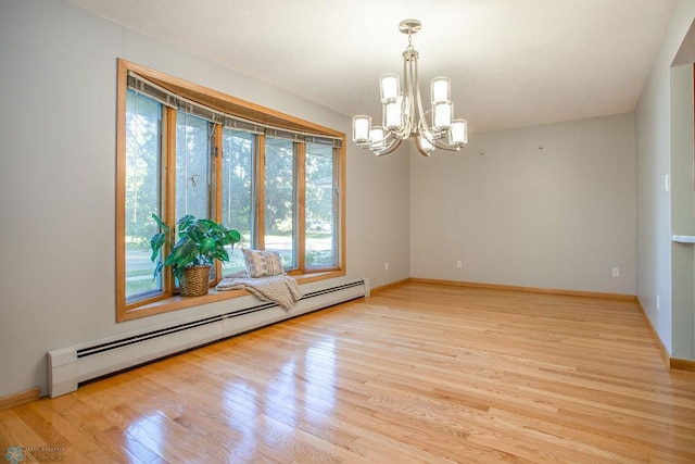 empty room featuring light hardwood / wood-style floors, an inviting chandelier, and a baseboard radiator