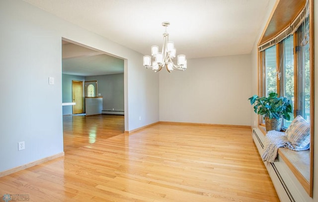 spare room with a chandelier, baseboard heating, and light hardwood / wood-style flooring