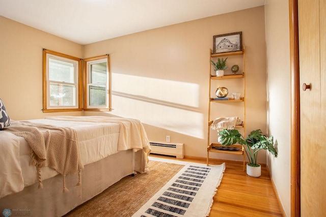 bedroom with baseboard heating and hardwood / wood-style floors