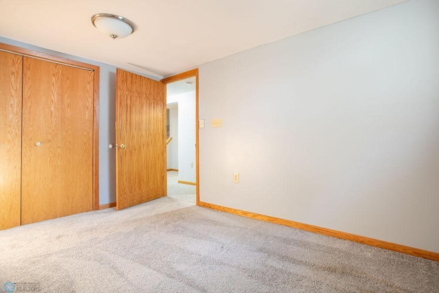 unfurnished bedroom with light colored carpet and a closet