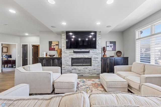 living room with a stone fireplace and light wood-type flooring