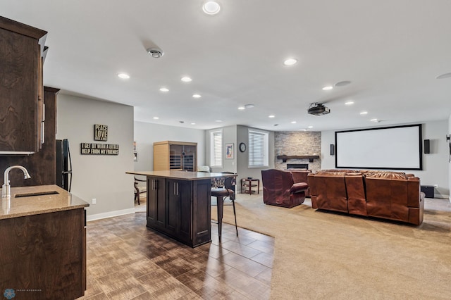 kitchen with a kitchen island, sink, carpet flooring, and dark brown cabinets