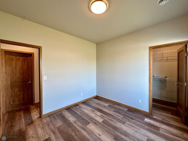 unfurnished bedroom featuring hardwood / wood-style flooring, a closet, and a walk in closet