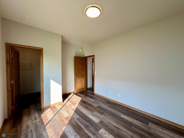 unfurnished bedroom featuring a closet, a walk in closet, and hardwood / wood-style flooring